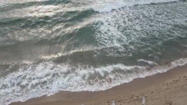 Deniz kıyısındaki güzel deniz dalgaları, deniz suyu köpükleri, güneşlenmek için kıyıda bekleyenler, insanlar yürür, spor yapar, insansız hava aracı, Nessebar, Bulgaristan 'ın üst manzarası