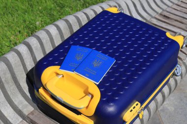 Ukrayna 'da yazılı 2 Ukrayna pasaportu - Ukrayna bayrağı renginde sarı mavi bavulda Ukrayna pasaportu bulunuyor. Seyahat, mülteciler, turizm, göç, seferberlik, göçmenler