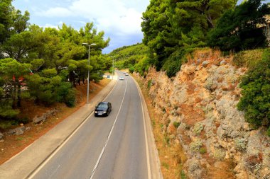 Hırvatistan 'daki dağ yolu yüksek dağlar, tepeler, çam ormanları arasında. Hırvat otoyolu, otobanı ve seyahatinde arabalar sürüyor
