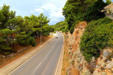 Mountain road in Croatia among high mountains, hills, pine forest. Cars drive on Croatian highway, autobahn, travel clipart