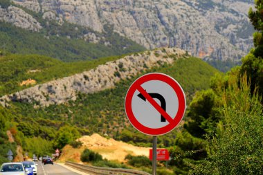 Yol işareti - sola dönmek yasak, beyaz zemin üzerinde siyah ok, kırmızıyla çizilmiş. Güzel dağlara karşı sola dönüş yok. Hırvatistan 'da yol yasağı tabelası