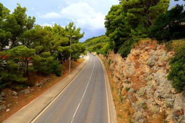Hırvatistan 'daki dağ yolu yüksek dağlar, tepeler, çam ormanları arasında. Hırvat otoyolu, otobanı ve seyahatinde arabalar sürüyor