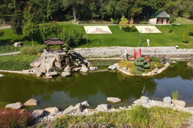A beautiful Japanese-style landscape park in New Sofiyivka. Lake, wooden arbors, red bridge, Aerial view from drone on park. Uman, Ukraine, 2021-09-12