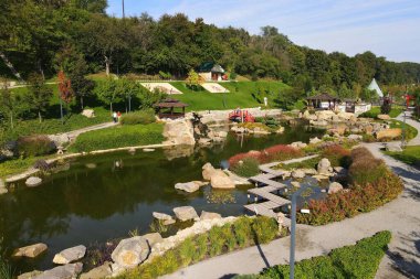 A beautiful Japanese-style landscape park in New Sofiyivka. Lake, wooden arbors, red bridge, Aerial view from drone on park. Uman, Ukraine, 2021-09-12