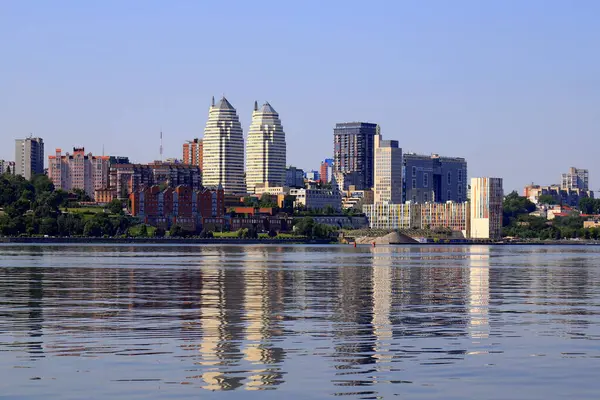 Geniş nehrin kıyısındaki büyük şehir. Güzel modern kuleler, binalar, gökdelenler yaz sabahı suya yansıyor. Su akıyor. Ukrayna şehri Dnipro, Dnepropetrovsk, Ukrayna