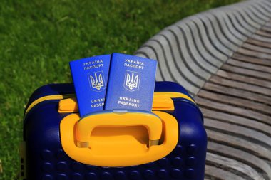 Ukrayna 'da yazılı 2 Ukrayna pasaportu - Ukrayna bayrağı renginde sarı mavi bavulda Ukrayna pasaportu bulunuyor. Seyahat, mülteciler, turizm, göç, seferberlik, göçmenler