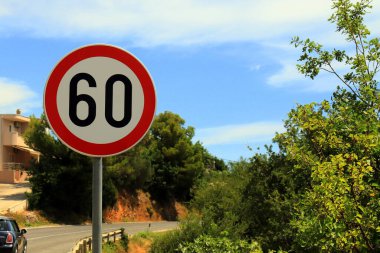 Hırvatistan 'da dağ yolunda trafik levhası 60, hız sınırı 60, seçici odaklanma. Arka planda trafik varken hız sınırı işareti
