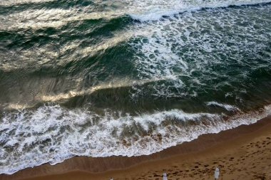 Deniz kıyısındaki güzel sahil, güneşlenmek için sahilde bekleyenler, insanlar yürüyor, spor yapıyor, insansız hava aracının üst manzarası, Nessebar, Bulgaristan