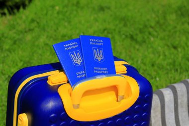 Ukrayna 'da yazılı 2 Ukrayna pasaportu - Ukrayna bayrağı renginde sarı mavi bavulda Ukrayna pasaportu bulunuyor. Seyahat, mülteciler, turizm, göç, seferberlik, göçmenler