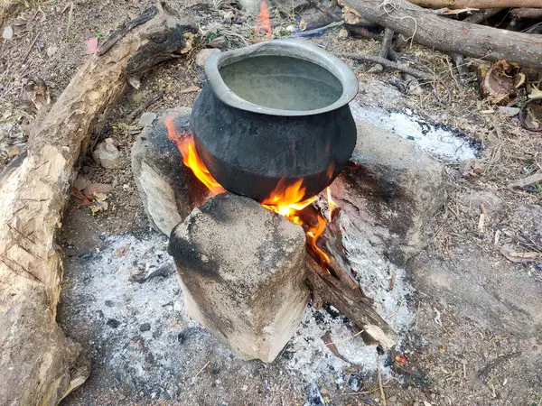 Geleneksel köy pişirme seti ve geçici soba. Açık ateşte su ısıtılıyor. Kırsal alanlar, kuru yapraklar, dallar. Nostaljiyi çağrıştırıyor, basit köy yaşamına bağlanıyor..