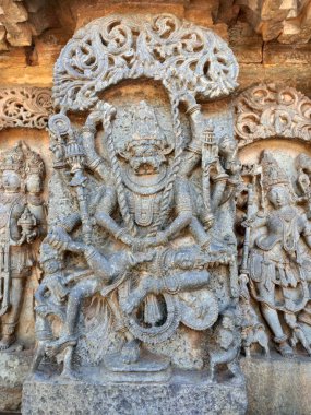 Stunning bas-relief of Ugra Narasimha, an avatar of Vishnu, adorns the Hoysaleswara Temple in Halebidu, India. The carving shows the fierce deity subduing demon king Hiranyakashipu with multiple arms.