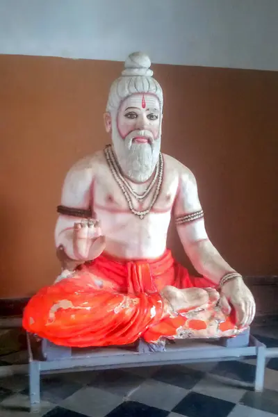 Beyaz sakallı, turuncu dhoti 'li ve boncuklu mücevherli bir Hindu heykelinin yıpranmış bir heykeli..