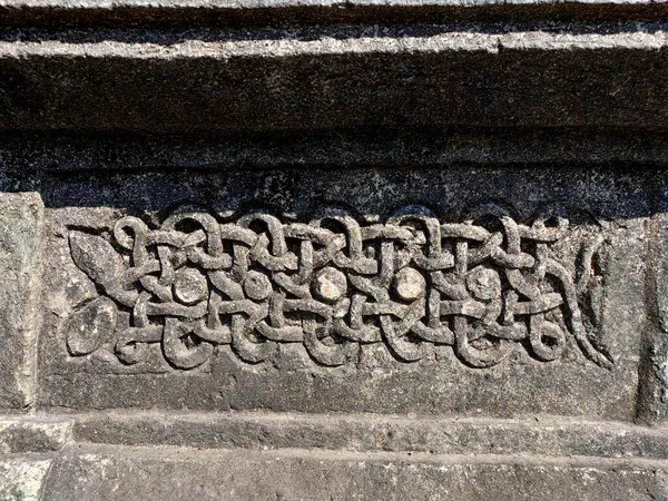 Karnataka 'daki Halebidu Tapınağı' nın duvarına oyulmuş bir yılanın detaylı bir yakın çekimi Hoysala sanatını gözler önüne seriyor, hassas ölçekler, sarmalanmış formlar, ve karmaşık ışık ve gölge ayrıntıları..