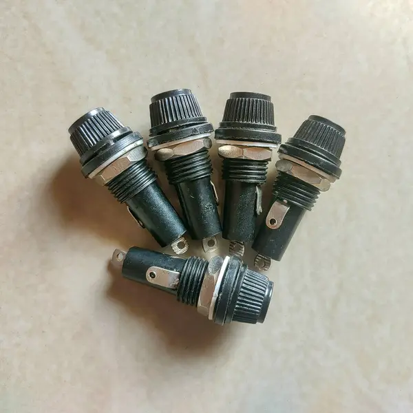 Bej bir yüzey üzerinde fan benzeri bir şablon içinde beş siyah panelli fünye tutucu. Silindirik, plastik ve metalden yapılmış, elektrik devrelerinde kullanılır. Elektronik ve endüstriyel görseller için ideal.