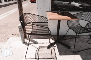 Metal tel sandalyeler ve güneşli bir köşenin yanındaki kafenin dışındaki ahşap masa, George Cafe Yeni Zelanda - Yaşam Tarzı Yeri