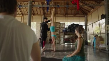 Yoga eğitmeni yoga dersine katılan öğrencinin duruşunu düzeltiyor. Grup etkinlik konsepti - 4K Yatay video