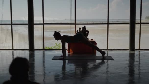 ビーチの隣にあるセンターでヨガのポジションを切り替える女性のシルエット 4K水平ビデオ — ストック動画