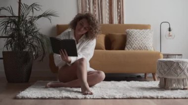 Genç bir kadın halı üzerine ilginç bir kitap okumaya odaklanmış - 4K Yatay Video