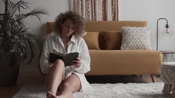 Λατινική Γυναίκα Διαβάζει Ένα Βιβλίο Κάθεται Στο Χαλί Στο Σαλόνι — Αρχείο Βίντεο
