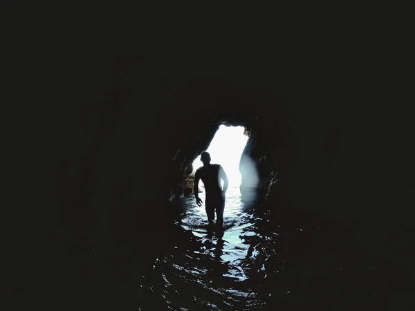洞窟の中の海の水の中のバックライトの少年 ライフスタイルトラベルコンセプト — ストック写真