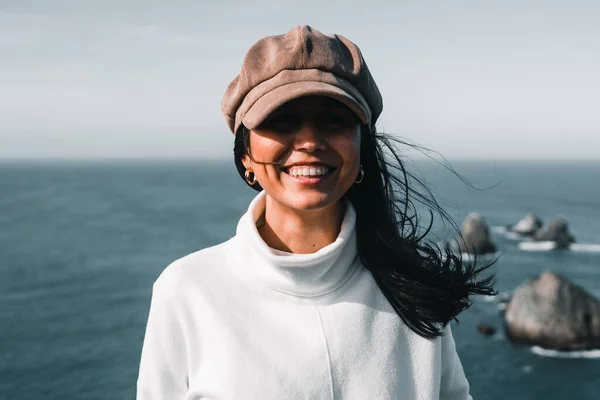 stock image caucasian brunette girl with long black hair smiling happy looking at camera in a quiet place near sea rocks, nugget point, new zealand - Travel concept