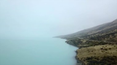 Deniz manzaralı ve dağların yanındaki yol bulutlu bir günde Yeni Zelanda, Cook Dağı 'nda.