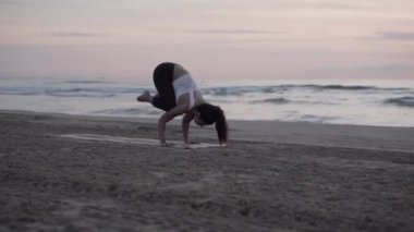 Playa Malvarrosa 'da yoga pozisyonunda dengede duran beyaz bir kız.
