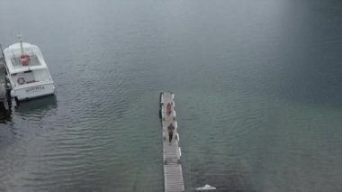 Deniz kenarında bir köprüde yürüyen bir çiftin hava görüntüsü, Yeni Zelanda - seyahat konsepti