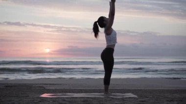 Güneşin doğuşunda kollarını kaldıran esmer kız İspanya 'da deniz kenarında ruhani bir öğretmen.