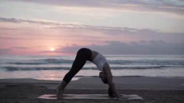 Doğu İspanya 'da kumsalda yoga egzersizi yapan esmer kadın.