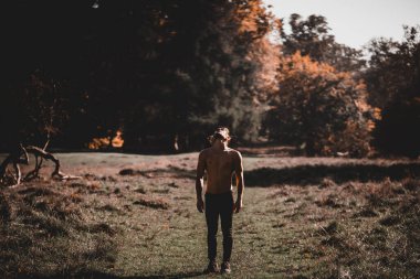 Üzerinde atkuyruğu olmayan beyaz bir adam ormana bakıyor. Seyahat konsepti.
