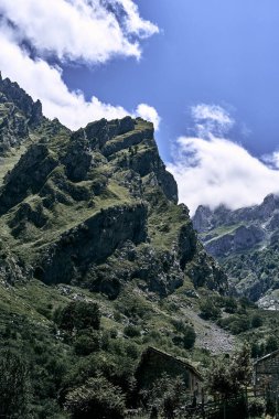 Bitkiler ve büyük kayalık dağlar arasındaki yolda küçük taş evler, Ruta del asturias, İspanya geleneksel yerleri umursuyor.