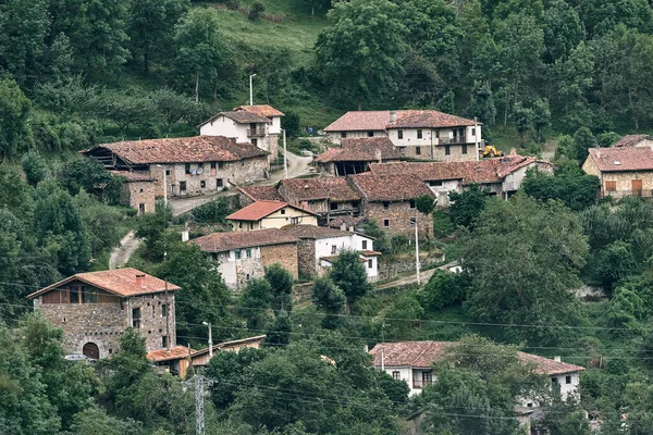 stock image small quiet village with old stone houses and brown roofs in the middle of the road next to the forest, ruta del cares asturias, spain - Spanish traditional places