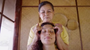 Profesyonel Tayland masözü, spa 'da çalışıyor. Genç bir kadın için gerginlik atma terapisi yapıyor. Yüz masajı - Tayland geleneği