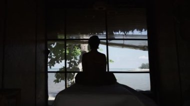 Sahil manzaralı bir kadın kaplıcada huzur içinde oturuyor. Rüzgar odanın içinde hareket ediyor - Tayland geleneği
