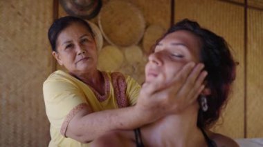 Taylandlı yaşlı masöz spa salonunda müşterilerinin boynunu geriyor. Kadın memnun ve rahat görünüyor - ağır çekim - Tayland geleneği