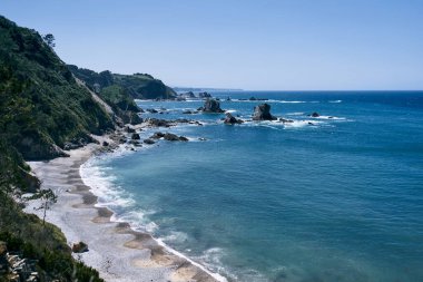 Yeşil ve mavi Cantabrian Denizi 'nin yanındaki küçük çakıl taşlı plajlara akan çimenlerle kaplı kayalık uçurumlar, asturyalar, İspanya - Asturian kavramı