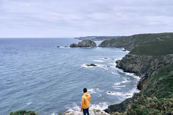 Arkadan gelen latin çocuk, sarı ceketiyle kıyıların ve kayalıkların güzelliğini düşünüyordu. Cabo de Penas, İspanya - İspanyol manzaraları.