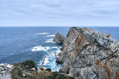 Büyük kayalıklarla ıssız kıyılarda deniz kenarında sakin bir yerde bulutlu bir günde Cabo de Penas, İspanya - İspanya manzaraları