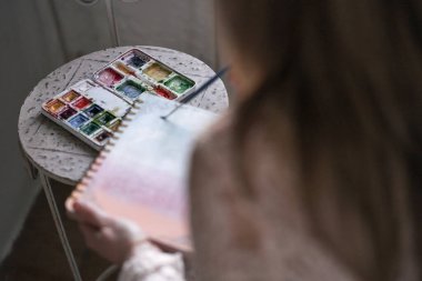 Bir kadının sol elinde yüzük klasörü ve üzerinde kayan bir fırça tutan sol elinin fotoğrafı.