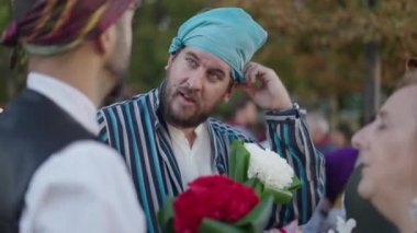 Sakallı adam, eşarbını ailesiyle konuşurken düzeltiyor. İspanyol gelenekleri.