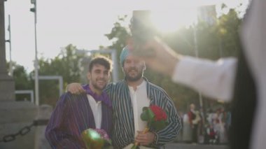 Yetişkin erkek eli sakallı ve elinde çiçekler olan iki genç adamın fotoğrafını çekiyor. İspanyol gelenekleri.