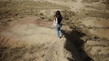Çöldeki bazı araçlara doğru bir tepeden inen genç kadın - İspanyol manzaraları