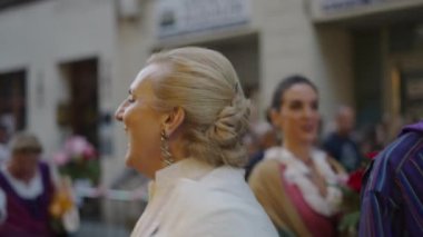 Yaşlı kadın İspanyol geleneklerine göre İspanya 'daki kalabalıkta öpücük ve dalgalar savuruyor.