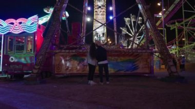 Eğlence parkında sallanan tekne şeklindeki eğlenceyi izleyen çift - İspanyol Fuarı konsepti