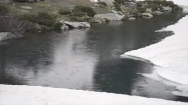 Yağmur damlaları düşerken dağın ortasında bir göl manzarası Alternatif seyahat
