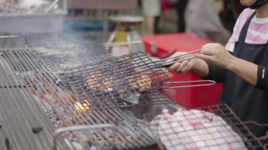 Bangkok Sokak Marketi 'nde ızgarada tavuk pişiren Asyalı bir kadının elleri.