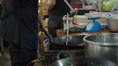 Siyah önlüklü adam Bangkok Bangkok Sokak Marketlerinde tava tipi tavaya sıvı döküyor.