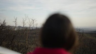 Kadının arabasının yanında dikilip yel değirmeni tarlasını gözlemlediği görüntüler.