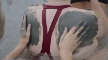 Genç kadınların elleri bir kadının sırtına çamur sürer Doğal Spa konsepti